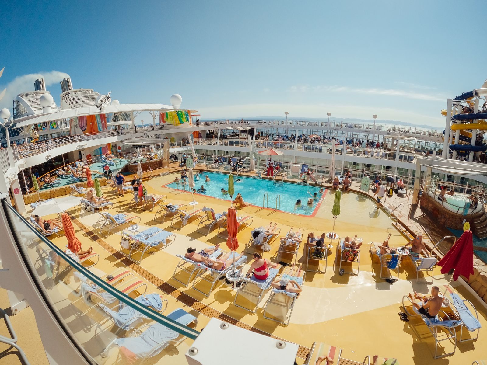 A busy pool deck on a large cruise ship with families on loungers and in the pool, typical of the lines that are best for families